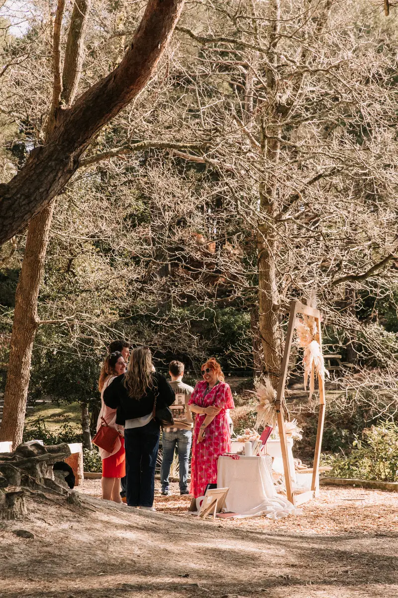A couple browse a supplier display beside the tipi under tall pines.