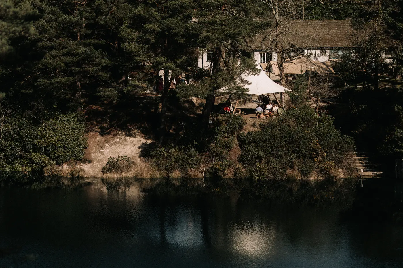 The tea room and the white tipi seen across the still turquoise water of the Blue Pool.