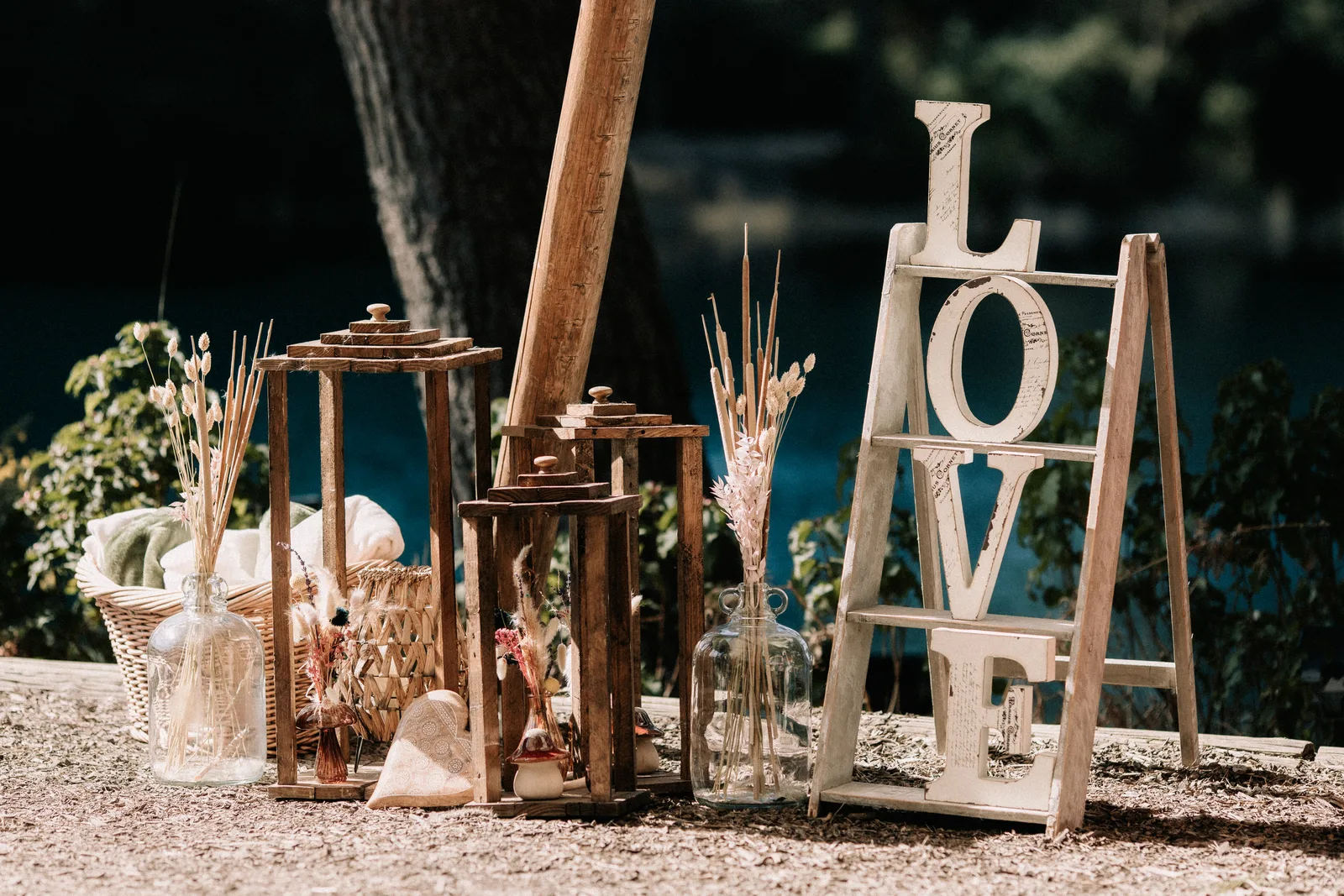 Wooden LOVE letters, lanterns and dried grasses set among the trees.