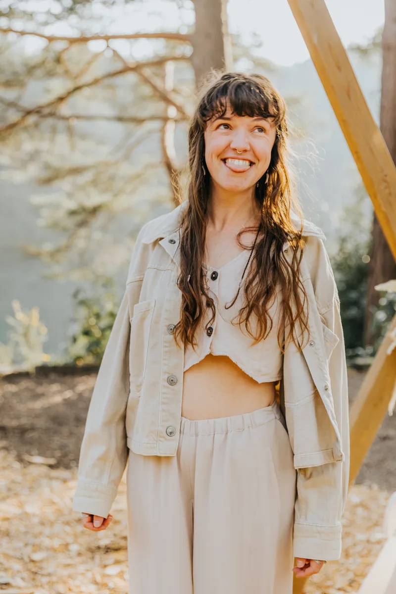 Jess laughing in a cream jacket in front of the arch, the lake behind her.